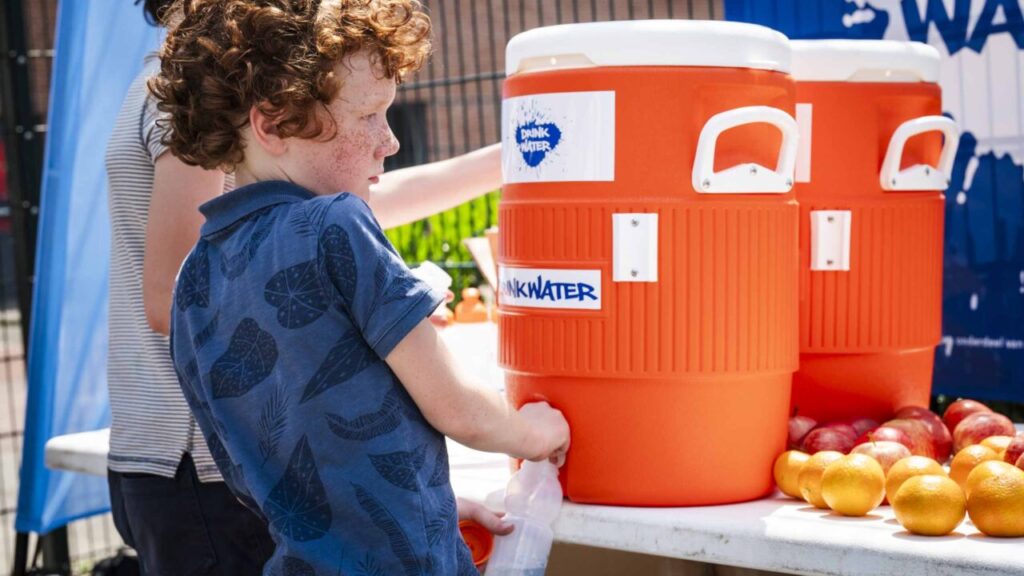 Kindje tapt water uit een waterton van JOGG