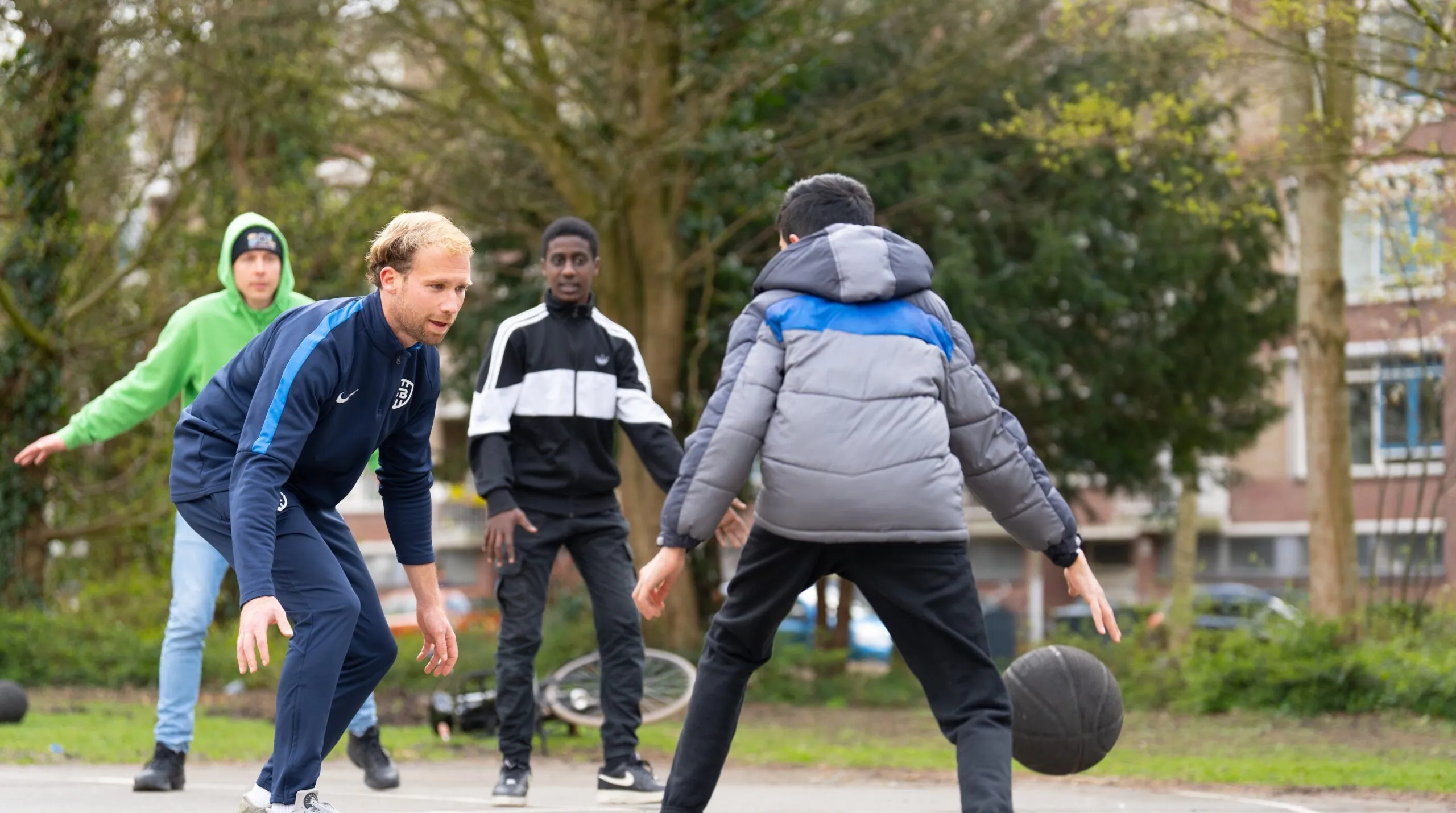 Jongens die buiten basketbal spelen met de buurtsportcoach